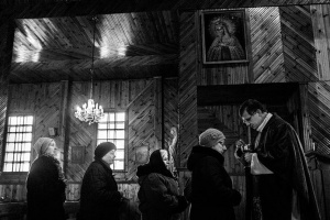 Священник Юстинас дает женщинам хлеб в конце службы /Фотограф: Ганс Юнг (Hannes Jung)